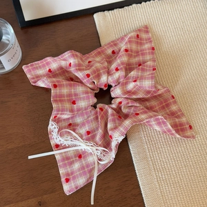 Dettaglio dell'elastico a scacchi con cuori rossi, pizzo bianco e fiocco satin