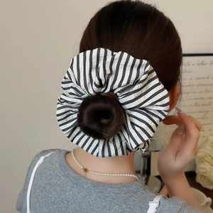 Detail of a large black and white striped fabric scrunchie worn on a messy hair bun