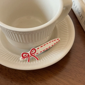 Detail of a white Korean hair clip with a red bow and polka dots on a metal duckbill base