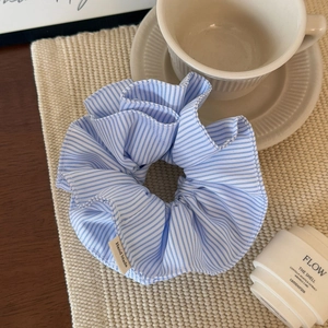 Detail of blue striped fabric scrunchie with a Hand Made woven label on a beige mat