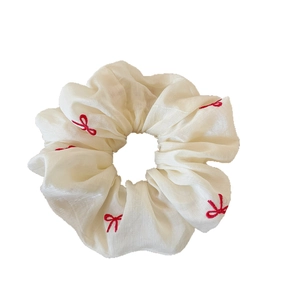 Elegant cream satin scrunchie featuring detailed red embroidered bow patterns for women
