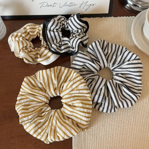 Set of four minimalist striped fabric hair scrunchies on a warm rustic wooden surface
