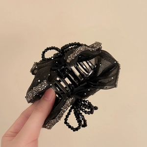 Detail of elegant black bow shark clip with rhinestones and organza texture