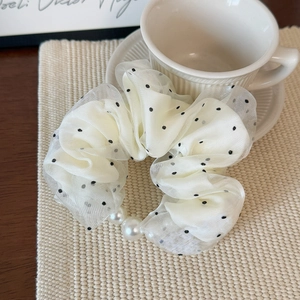 Detailed close-up of cream polka dot organza scrunchie with elegant large white pearls