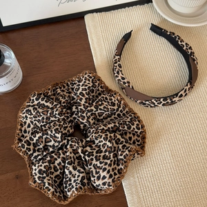 Leopard print scrunchie and headband set made of textured fabric on a wooden table