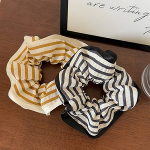 Close-up of yellow and black striped fabric scrunchies on a wooden background