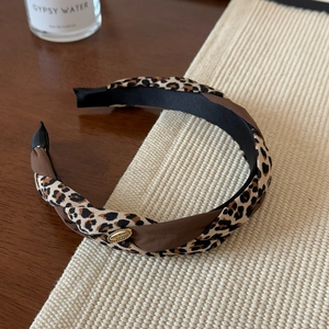 Detail of twisted leopard print headband with a gold metal charm and vintage fabric texture