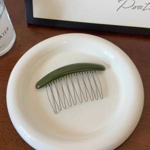Gros plan du peigne à cheveux vert olive avec 11 dents en métal argenté sur une assiette