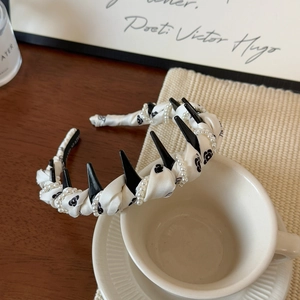 Elegant woven headband with white pearls, black spikes, and camellia floral patterns