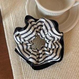 Close-up of black and white striped fabric scrunchie on a cozy woven tray with cup