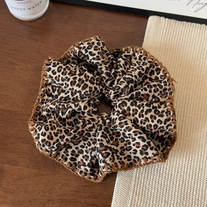 Close-up of leopard print scrunchie showing fabric texture and brown stitched edges