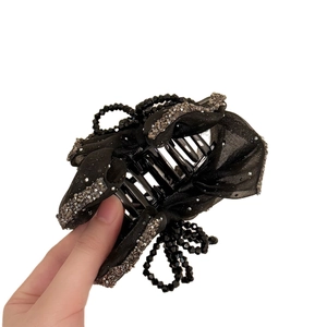 Elegant black bow hair claw clip with shimmering rhinestones and black crystal beads