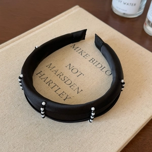 Détail d'un serre-tête noir rembourré avec perles brodées à la main et élégantes
