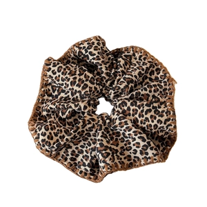 Fashionable leopard print oversized scrunchie with fine brown stitching on white background