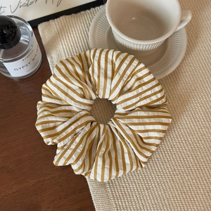 Close-up of yellow and white striped fabric scrunchie on a warm wooden tabletop