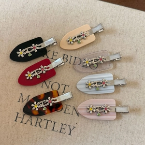 Ensemble de barrettes à fleurs en métal en sept couleurs sur fond de toile texturée