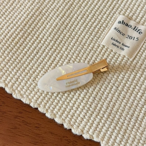 Minimalist leaf-shaped acetate hair clip with pearl texture and golden metal finish