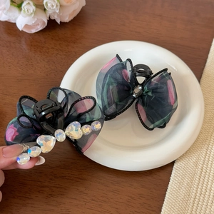 Dettaglio di fermagli per capelli in organza floreale con strass a cuore sfumati