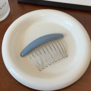 Détail du peigne à cheveux en métal à 10 dents avec dessus en résine bleue sur céramique
