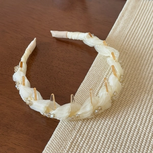 Détail d'un serre-tête tressé crème avec dents antidérapantes et perles scintillantes