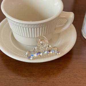 Close-up of small transparent hair claw with iridescent crystals on ceramic cup