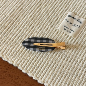 Detailed macro view of the black and white checkered pattern on a golden duckbill hair clip