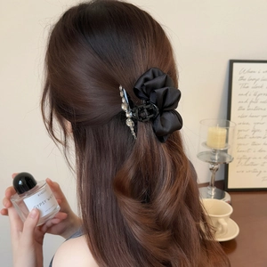 Détail de la pince à cheveux en satin noir avec strass portée sur modèle en lumière chaude
