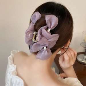 Detail view of a lavender organza bow hair claw clip with sequins on a bun hairstyle