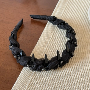 Détail du serre-tête noir tressé avec pointes punk et perles facettées sur la texture