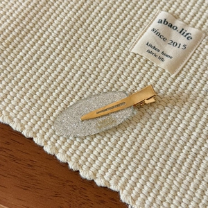Close-up of a silver glitter hair clip with a golden metal duckbill base on fabric