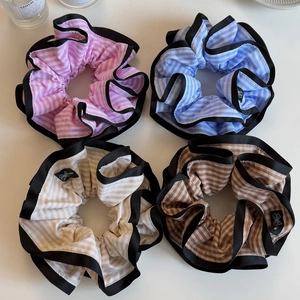 Detail view of four striped scrunchies in pink, blue, beige, and coffee with black piping