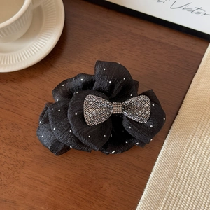 Detailed view of the black satin hair claw with a large crystal studded bow design