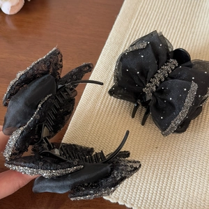Detail von schwarzer Organza-Schleifen-Haarklammer mit silbernen Pailletten auf Unterlage