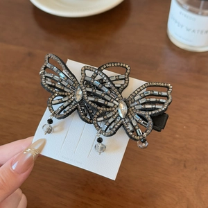 Close-up of hollow butterfly hair clip with sparkling crystals and black bead charms