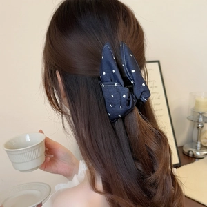 Denim fabric shark hair clip with white heart prints worn on long wavy hair in cozy setting