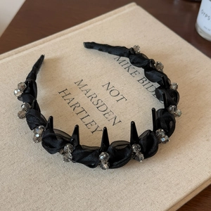 Detail of black mesh headband featuring decorative spikes and sparkling clear beads