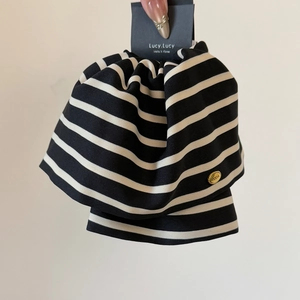 Detail of a large black and white striped ponytail clip with a gold metal tag