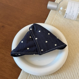 Detail shot of navy denim fabric hair clip with white heart prints on a ceramic plate