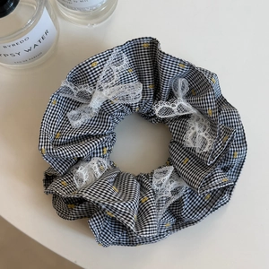 Détail du chouchou à carreaux avec nœuds en dentelle blanche et motifs à pois jaunes