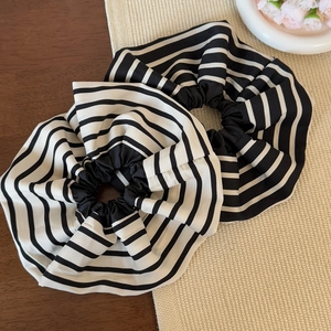 Détail de deux chouchous élastiques à rayures noires et blanches sur une surface en bois