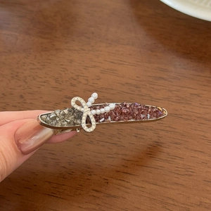 Elegant rhinestone duckbill hair clip with bow and pearls on a vintage gray crystal base