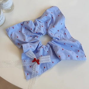 Détail d'un chouchou à carreaux bleus avec nœud en dentelle blanche et broderie