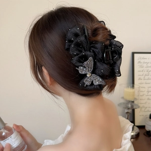 Détail d'une pince à cheveux noire élégante avec nœud en strass sur une demi-queue