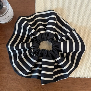 Détail macro du chouchou français rayé noir et blanc en tissu sur un décor en bois