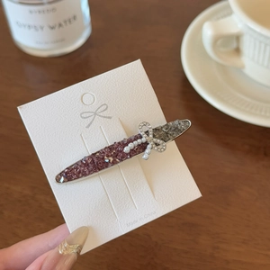 Detail of a sparkling rhinestone hair clip with a pearl bow on a display card