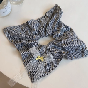 Détail de chouchou à carreaux noirs et blancs avec nœud jaune et dentelle blanche