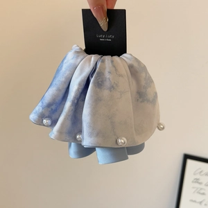 Gros plan d'un chouchou bleu marbré avec bordure en perles et texture satinée élégante