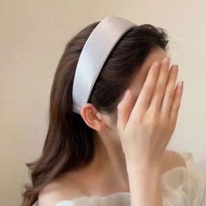 Detail of elegant satin sponge headband with a pearl-like glossy finish on a female model