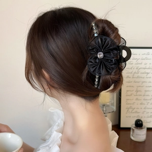 Grande pince à cheveux fleur noire élégante avec strass portée par un mannequin