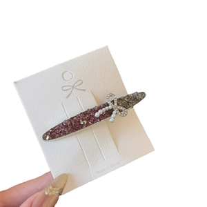 Sparkling crystal hair clip with silver bow and pearl detail on white display card